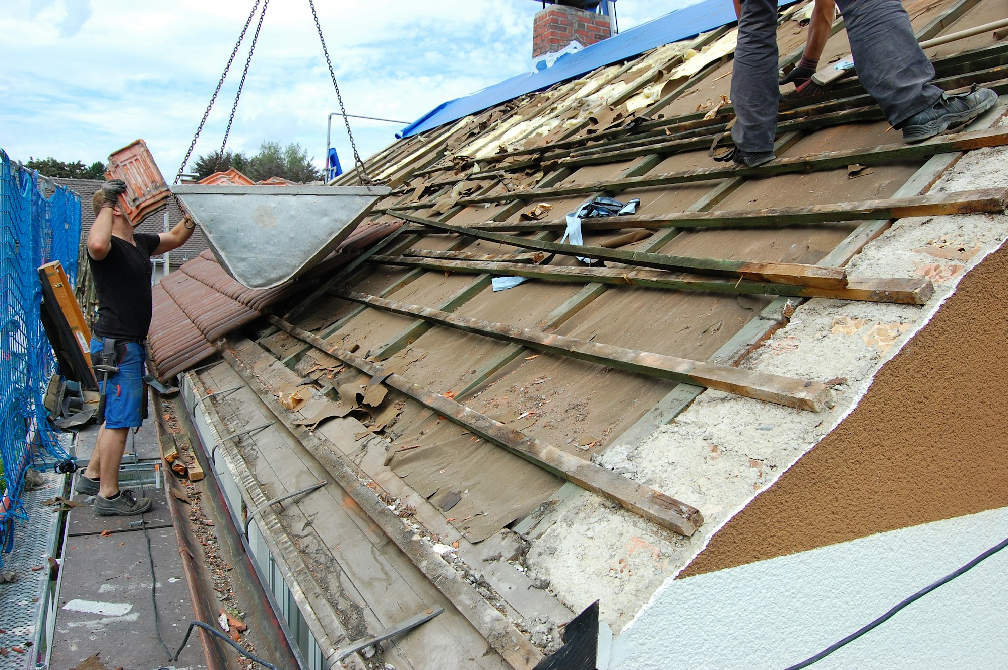 Builder removing old roof tiles from an open roof