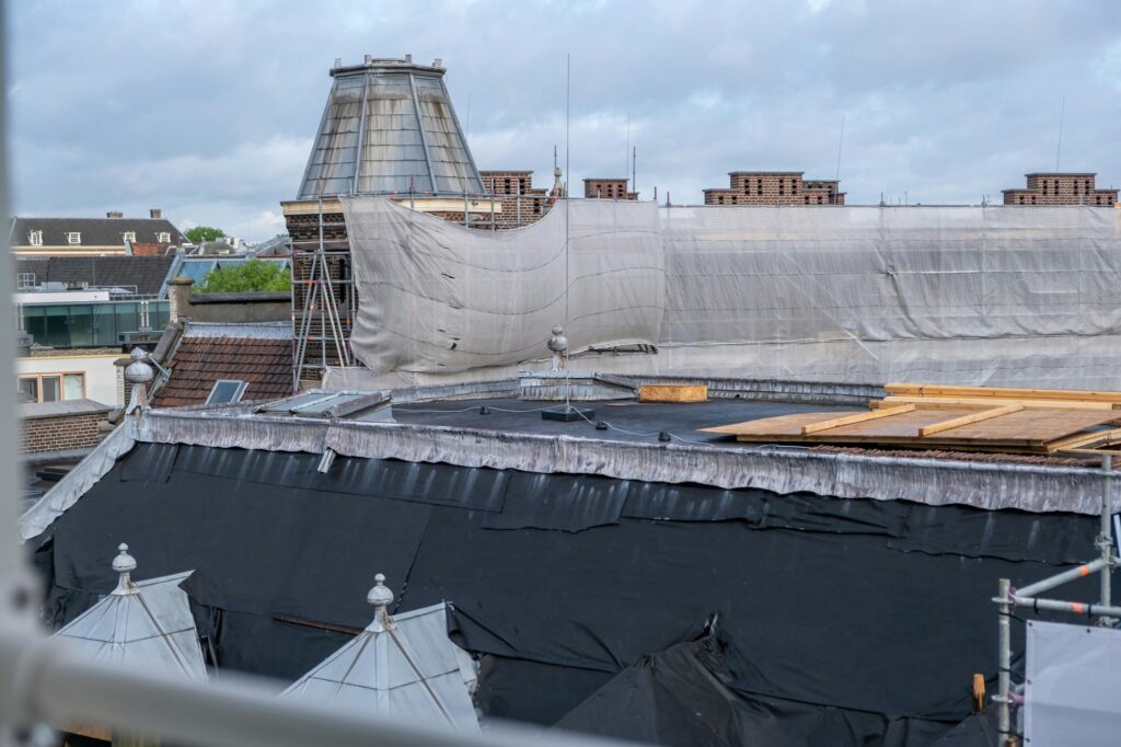 Roof construction, insulation work. Metal scaffolding, timber and waterproof membrane at rooftop.