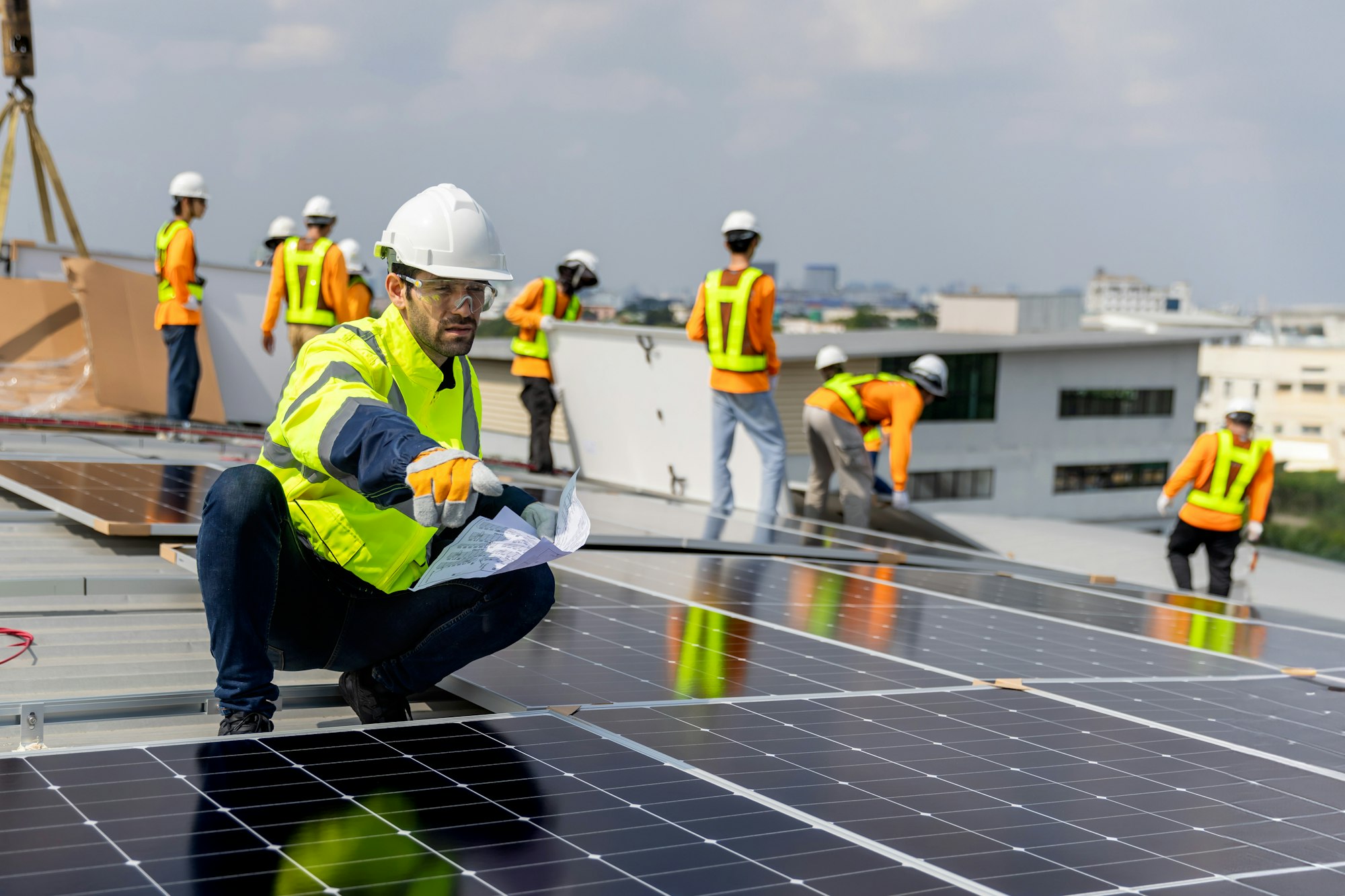 Technicians Install photovoltaic solar modules on roof of factory.