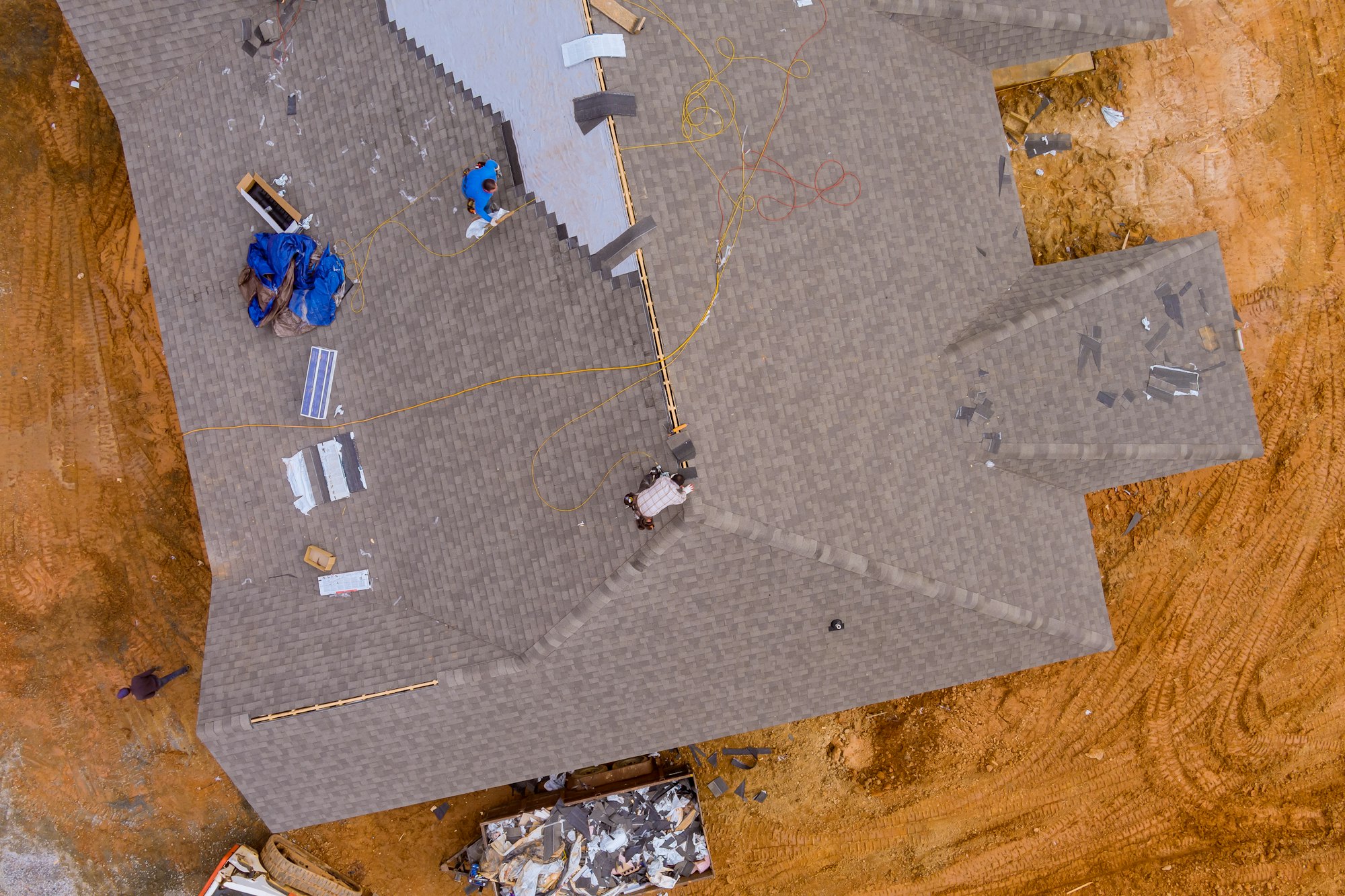 There is a construction roofer on the roof of the house installing new roof shingles